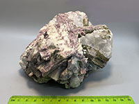 a chunk of crystalline rock with large pink and green, and white crystals